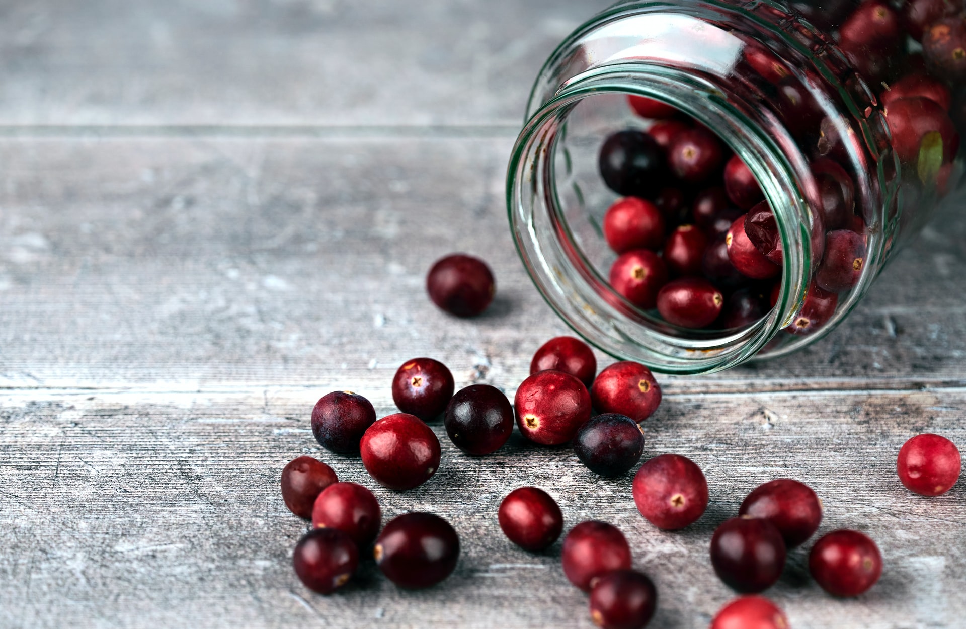 Photo of some cranberries spilling out of a glass jar