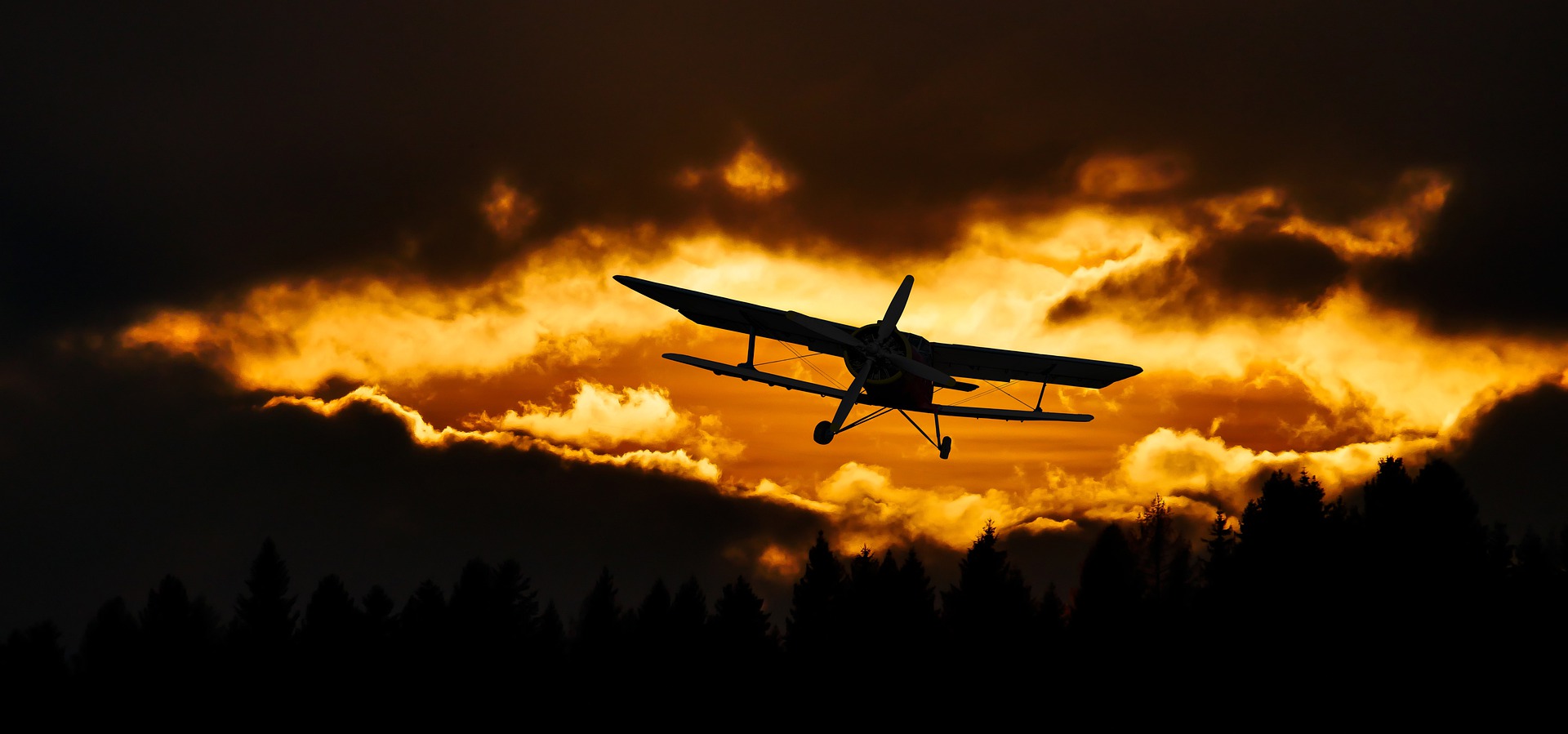 Image of a biplane flying towards clouds