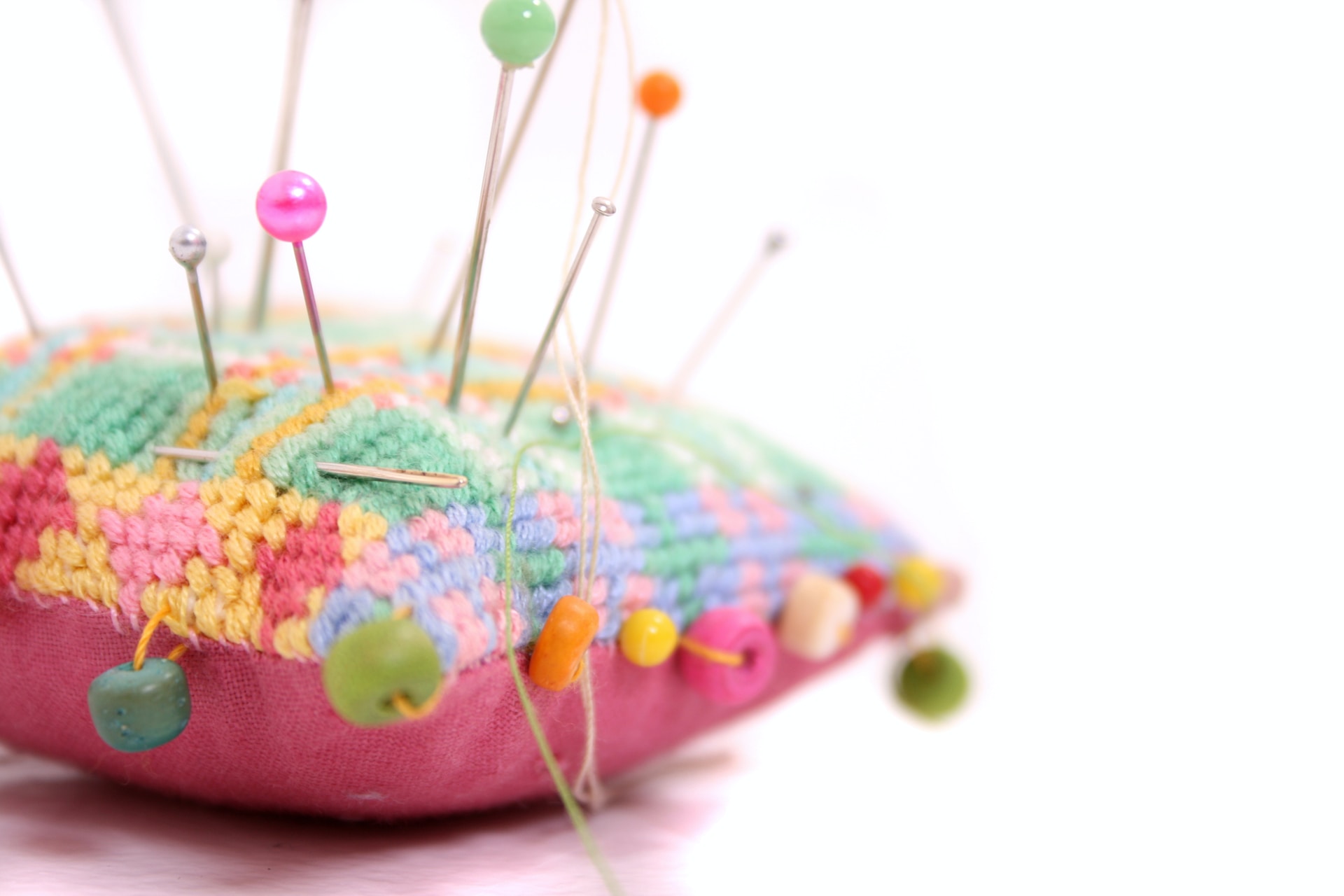 Numerous pins pushed into a colourful pin cushion